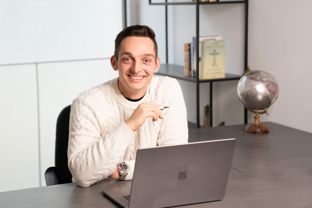 Mann am Schreibtisch mit Laptop und Kugelglobus.